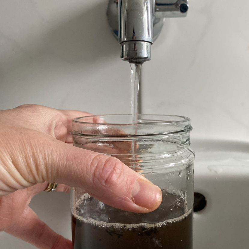 Einmachglas gefüllt mit Erde wird mit Wasser gefüllt